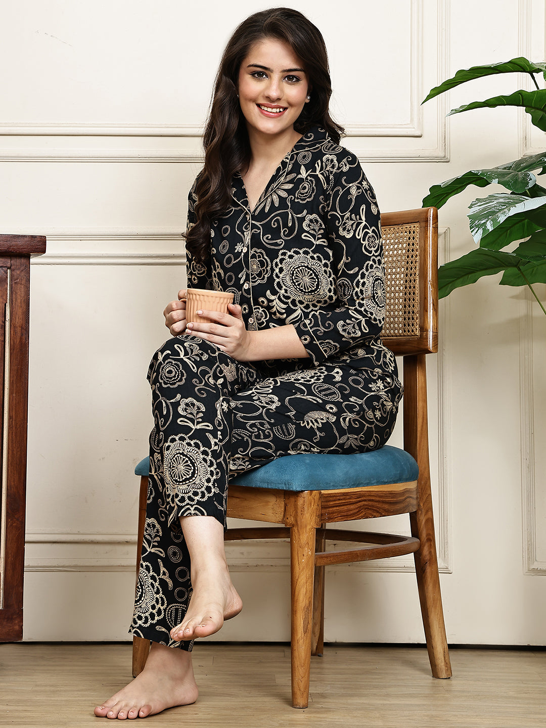 Woman relaxing on a bed in a black ethnic print night suit for women.
